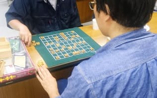 ひきこもりの人が集う居場所「よりどころ」でスタッフと将棋をする男性（手前、7月、札幌市）=共同