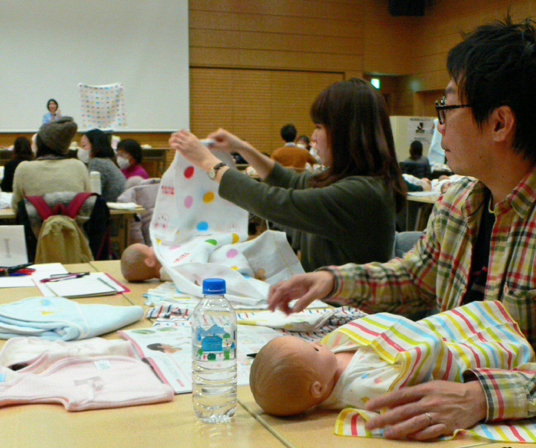 出産前の夫婦を対象にしたセミナーで乳児の世話の仕方を学ぶ男性(右)