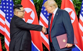 首脳会談で握手するトランプ米大統領と北朝鮮の金正恩委員長（6月12日、シンガポール）=ロイター