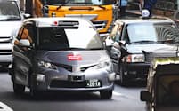実証実験で公道を走行する自動運転タクシー（左）（27日午前、東京都港区）