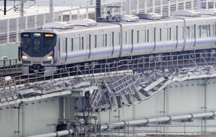 運転を再開し、タンカー衝突の爪痕が残る関西空港連絡橋を走るJRの始発列車(18日)=共同 運転を再開し、タンカー衝突の爪痕が残る関西空港連絡橋を走るJRの始発列車(18日)=共同