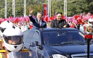 18日、平壌の沿道を埋めた市民に手を振って応える韓国の文在寅大統領(左)=平壌写真共同取材団撮影
