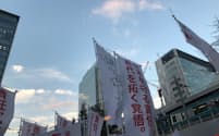19日、JR秋葉原駅前の演説会場では支持と批判ののぼりが交錯した