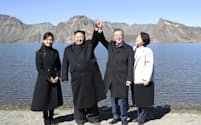 朝鮮半島最高峰の白頭山を訪問し、カルデラ湖「天池」でつないだ手を上げる北朝鮮の金正恩朝鮮労働党委員長（中央左）と韓国の文在寅大統領（同右）。夫人が同行した（20日）=平壌写真共同取材団撮影