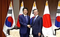 25日、ニューヨークでの会談前に韓国の文在寅大統領（右）と握手する安倍首相=共同