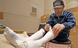 避難所で医療用弾性ストッキングをはく男性(26日、北海道安平町)=共同 避難所で医療用弾性ストッキングをはく男性(26日、北海道安平町)=共同