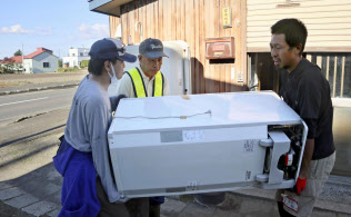 台風の接近を警戒し、北海道地震の被災者の自宅前でごみとなった冷蔵庫を運び出すボランティアら(29日、北海道安平町)=共同 台風の接近を警戒し、北海道地震の被災者の自宅前でごみとなった冷蔵庫を運び出すボランティアら(29日、北海道安平町)=共同