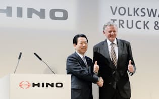 記者会見で握手する日野自動車の下義生社長と独VW傘下の商用車持ち株会社のアンドレアス・レンシュラーCEO（今年4月、東京・港）