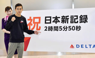 シカゴ・マラソンから帰国し、横断幕の前でポーズを取る大迫傑選手(10日、成田空港)=共同 シカゴ・マラソンから帰国し、横断幕の前でポーズを取る大迫傑選手(10日、成田空港)=共同