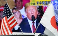 日米国旗と米中間選挙を報じるニュース映像（7日午前、東京都港区の外為どっとコム）