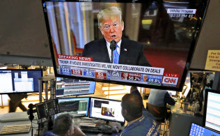 ニューヨーク証券取引所のモニターで放映されるトランプ大統領の記者会見(7日)=AP ニューヨーク証券取引所のモニターで放映されるトランプ大統領の記者会見(7日)=AP