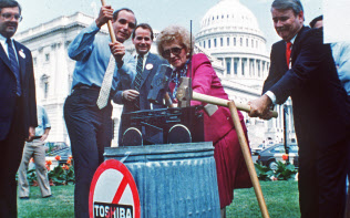 1987年7月、米議会前で東芝製ラジカセをハンマーでたたき壊す米議員ら=AP 1987年7月、米議会前で東芝製ラジカセをハンマーでたたき壊す米議員ら=AP