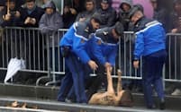 トランプ大統領の車列に近づき、護衛に取り押さえられる上半身裸の女性（11月11日、パリ）=ロイター
