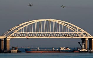 25日、3隻のウクライナ艦船がアゾフ海入りを阻止された後、ロシアとクリミア半島を結ぶ橋の上空を飛ぶ同国の戦闘機=ロイター