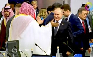 30日、Ｇ20会議でムハンマド皇太子とハイタッチするプーチン大統領（ブエノスアイレス）＝ロイター