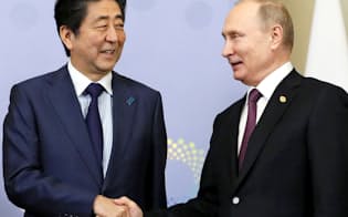 首脳会談前にロシアのプーチン大統領（右）と握手する安倍首相（1日、ブエノスアイレス）=共同