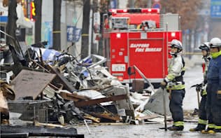 爆発のあった建物付近を調べる消防隊員ら。けが人は計42人に上る（17日午前、札幌市豊平区）=共同