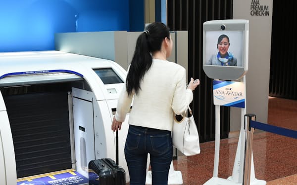 羽田空港での実証実験では、業務スタッフが遠隔操作したアバターロボット(右)で旅行者を案内した