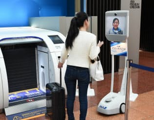 羽田空港での実証実験では、業務スタッフが遠隔操作したアバターロボット(右)で旅行者を案内した