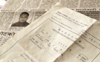 難民認定証明書（手前）と、来日前に拘束された時のことを報じるネパールの新聞=上間孝司撮影