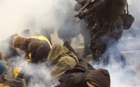 米シアトルのWTO閣僚会議場周辺でデモ隊を排除するための催涙ガスを放つ警察隊（1999年11月30日）=ロイター