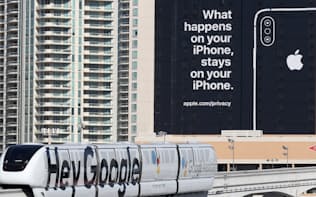 プライバシーに配慮していることを訴える米アップルの看板。下をグーグルの広告が入ったモノレールが走る（9日、米ラスベガス）=玉井良幸撮影