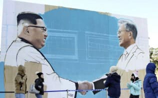 韓国大統領府前にある広場で作成中の文在寅大統領と北朝鮮の金正恩委員長が握手する絵(8日、ソウル)=共同 韓国大統領府前にある広場で作成中の文在寅大統領と北朝鮮の金正恩委員長が握手する絵(8日、ソウル)=共同