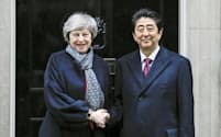 10日、会談前に握手する英国のメイ首相（左）と安倍首相（ロンドン）=共同