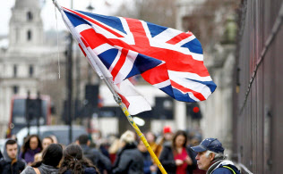 16日、ロンドンの英議会前で英国旗を持つ男性=ロイター 16日、ロンドンの英議会前で英国旗を持つ男性=ロイター