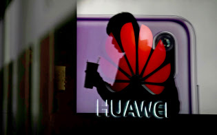 ガラス戸に反映したファーウェイのロゴ(上海)=ロイター ガラス戸に反映したファーウェイのロゴ(上海)=ロイター
