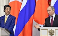 日ロ首脳会談後の共同記者発表で発言するプーチン大統領(右)（22日、モスクワ）=ロイター