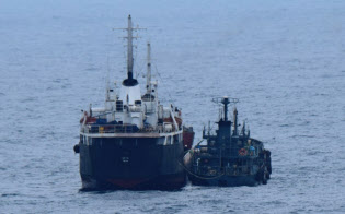 海上自衛隊が撮影した東シナ海での「瀬取り」。北朝鮮船籍のタンカー(左)に船籍不明の小型船舶がホースを接続している=防衛省提供 海上自衛隊が撮影した東シナ海での「瀬取り」。北朝鮮船籍のタンカー(左)に船籍不明の小型船舶がホースを接続している=防衛省提供