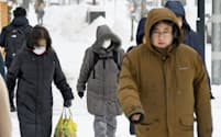防寒具を着込んで歩く人たち（8日午前、札幌市）=共同
