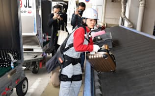 パワーアシストスーツを装着して手荷物を持ち上げるJALグランドサービスの社員（12日、羽田空港）