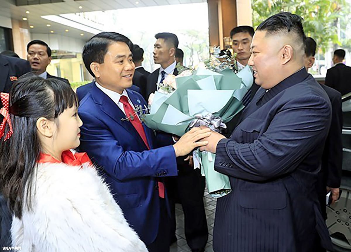 ハノイのホテルに到着し、ベトナム側関係者から花束を受け取る北朝鮮の金正恩朝鮮労働党委員長(右、VNA=共同)