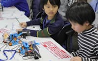 ロボットを動かすプログラムに真剣な表情で取り組む子供たち（東京都中野区）