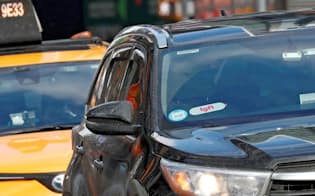 ニューヨークの路上でリフトのロゴをフロントガラスにつけているライドシェアの車がタクシーの前を走っている=ロイター