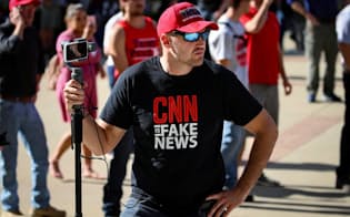 「CNNはフェイクニュースだ」と書かれたTシャツを着るトランプ大統領の支持者=ロイター