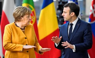 3月22日、ブリュッセルでのEU首脳会議に向かうメルケル独首相(左)とマクロン仏大統領=ロイター 3月22日、ブリュッセルでのEU首脳会議に向かうメルケル独首相(左)とマクロン仏大統領=ロイター