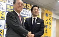 握手する国民民主党の玉木代表（右）と自由党の小沢共同代表（26日未明、東京・永田町）
