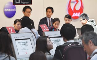 旅客システムに不具合が発生し、搭乗手続きで混雑する日本航空のカウンター（8日午前、羽田空港）