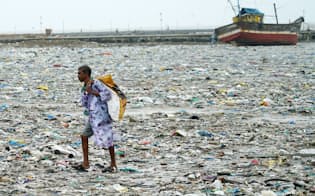 海岸に打ち上げられたプラスチックごみを集める男性（2018年7月、インド・ムンバイ近郊）
