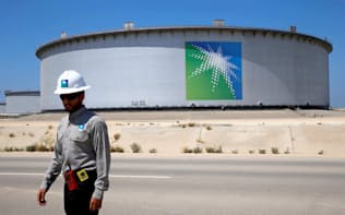 サウジアラビア国営石油会社、サウジアラムコの貯蔵タンクの近くを歩く従業員（2018年5月、サウジ国内の石油精製施設）=ロイター