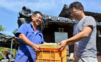 地元の養鶏業者から差し入れの卵を受け取る成田剛史さん(左)（千葉県南房総市）