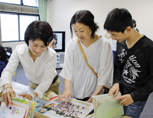 斎藤裕子さん(左)らが修復した思い出の品を受け取る小倉智美さん(中央)と息子の翔さん(25日午前、岡山市)=共同 斎藤裕子さん(左)らが修復した思い出の品を受け取る小倉智美さん(中央)と息子の翔さん(25日午前、岡山市)=共同