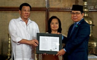 反政府武装勢力を率いたムラド氏(右)はドゥテルテ大統領(左)の呼び掛けた和平に応じた=ロイター 反政府武装勢力を率いたムラド氏(右)はドゥテルテ大統領(左)の呼び掛けた和平に応じた=ロイター