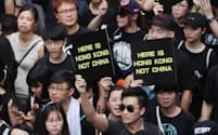 「ここは香港だ。中国ではない」と書かれたプラカードを掲げ、デモ行進する人たち（16日、香港）=三村幸作撮影