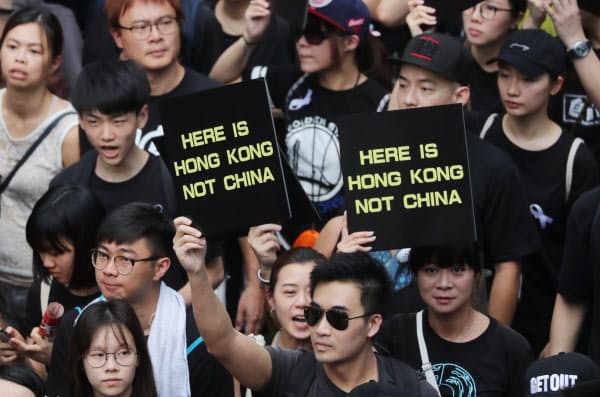 「ここは香港だ。中国ではない」と書かれたプラカードを掲げ、デモ行進する人たち（16日、香港）=三村幸作撮影