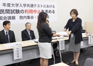 英語民間試験の利用中止を求める要請文を、文科省の担当者に渡す京都工芸繊維大の羽藤由美教授(右)(18日午後、東京都内)=共同 英語民間試験の利用中止を求める要請文を、文科省の担当者に渡す京都工芸繊維大の羽藤由美教授(右)(18日午後、東京都内)=共同