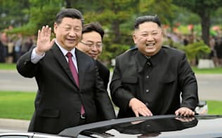 オープンカーから沿道の市民に手を振る習近平国家主席と金正恩委員長(右)（20日、平壌）=朝鮮中央通信・共同